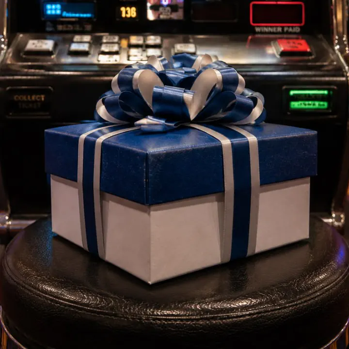 Blue-and-white gift box in front of a casino slot machine.